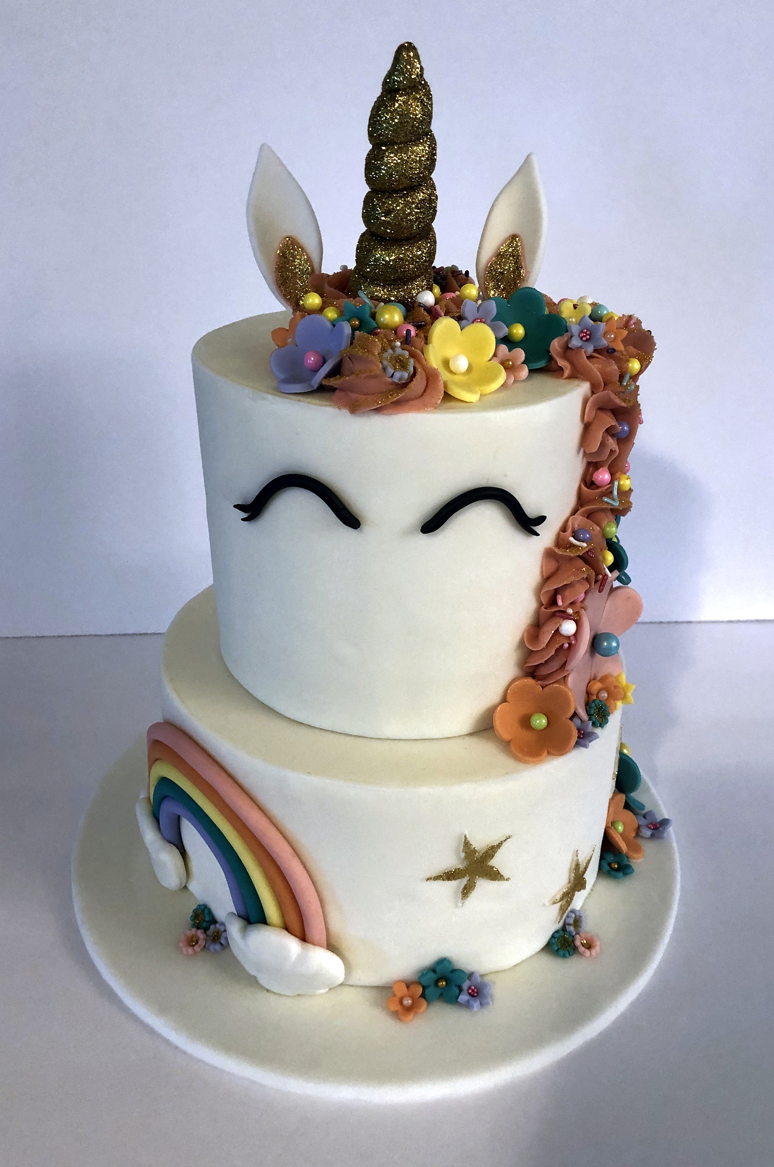 A unicorn themed 2-tier custom birthday cake with buttercream details from Village Patisserie in Toledo, Ohio
