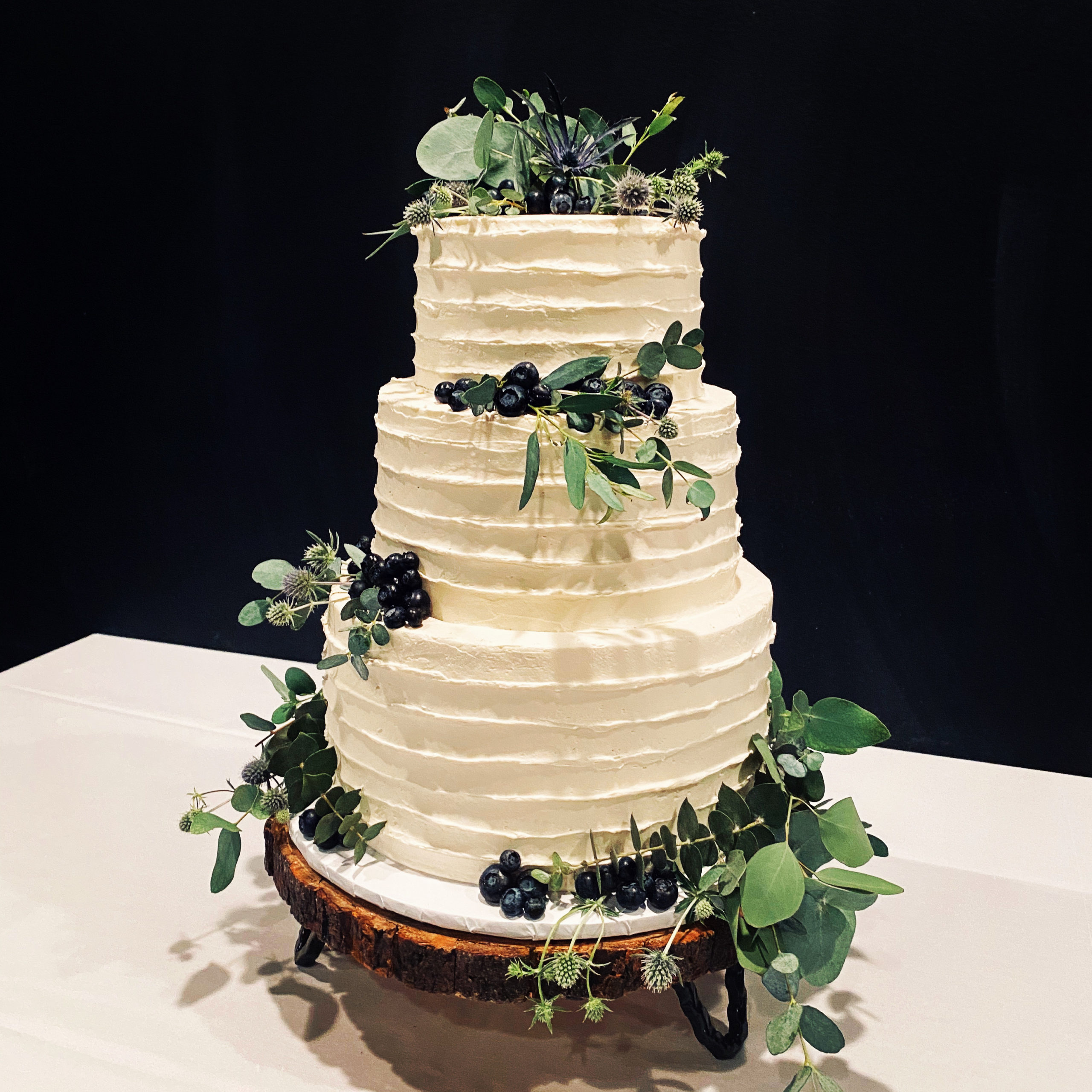 A beautiful 3-tier custom wedding cake with horizontal texture and fresh greenery from Village Patisserie in Toledo, Ohio