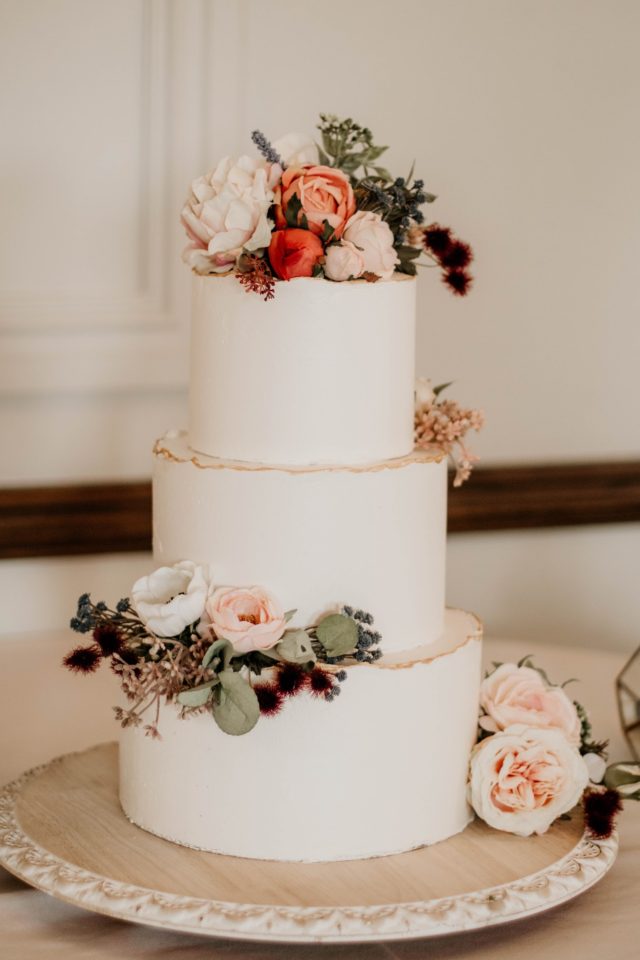 A beautiful 3-tier custom wedding cake with gold sugar sheet edges and live flowers from Village Patisserie in Toledo, Ohio
