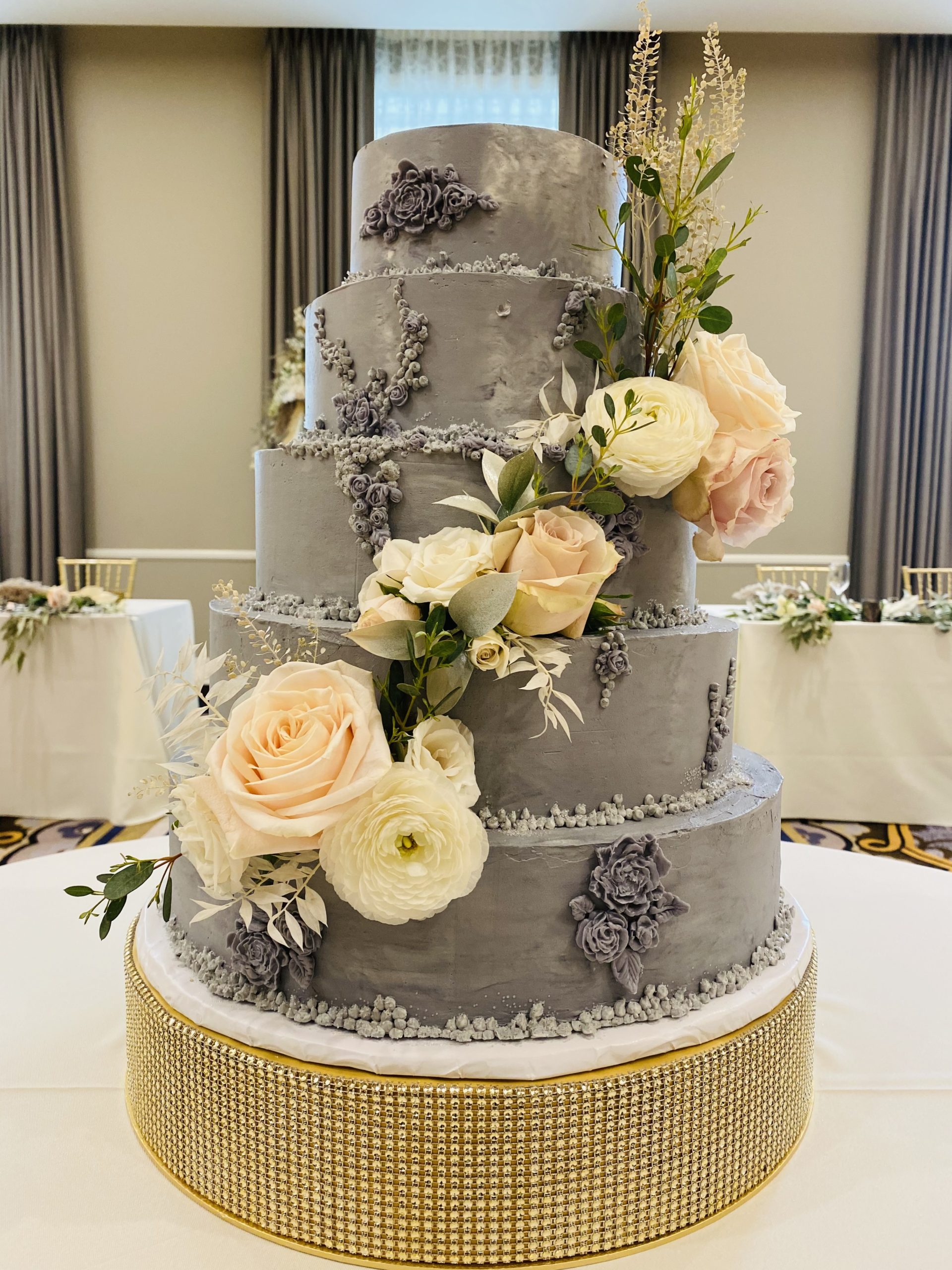 A beautiful 5-tier custom wedding cake in mauve buttercream with intricate frosted flowers and a live floral spray from Village Patisserie in Toledo, Ohio