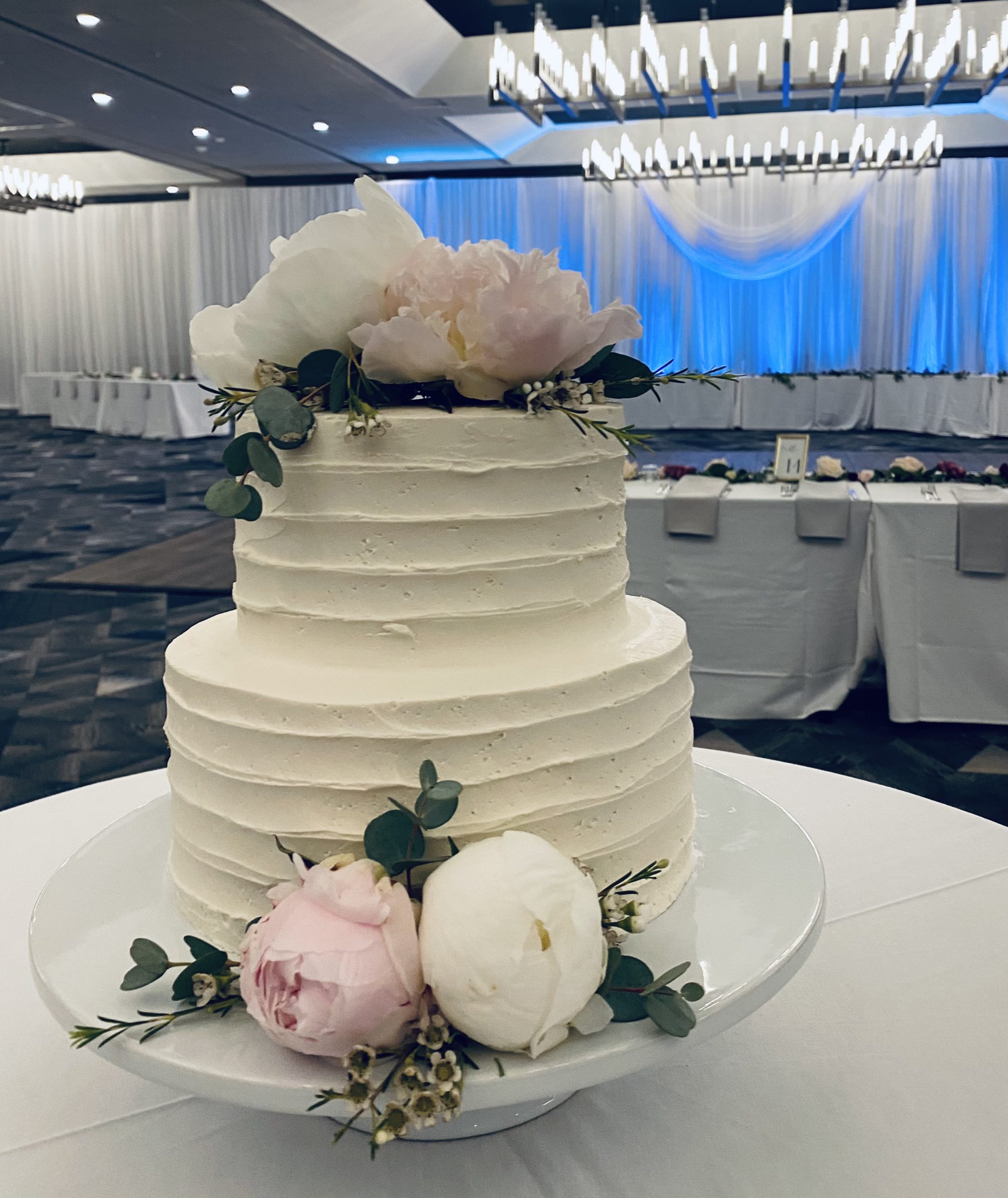 A beautiful 2-tier custom wedding cake with horizontal texture and live flowers from Village Patisserie in Toledo, Ohio