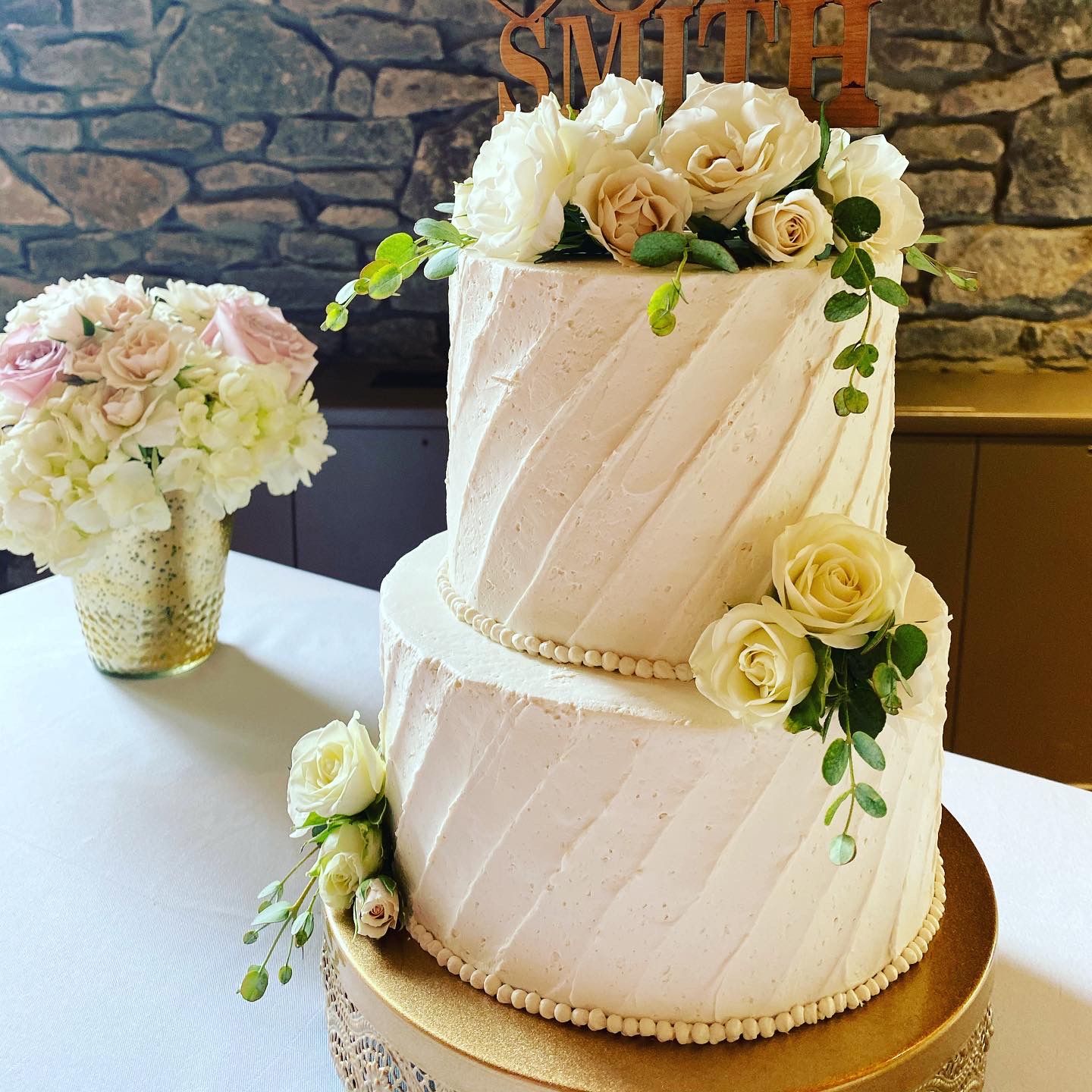 A beautiful 2-tier custom wedding cake with diagonal texture and live flowers from Village Patisserie in Toledo, Ohio