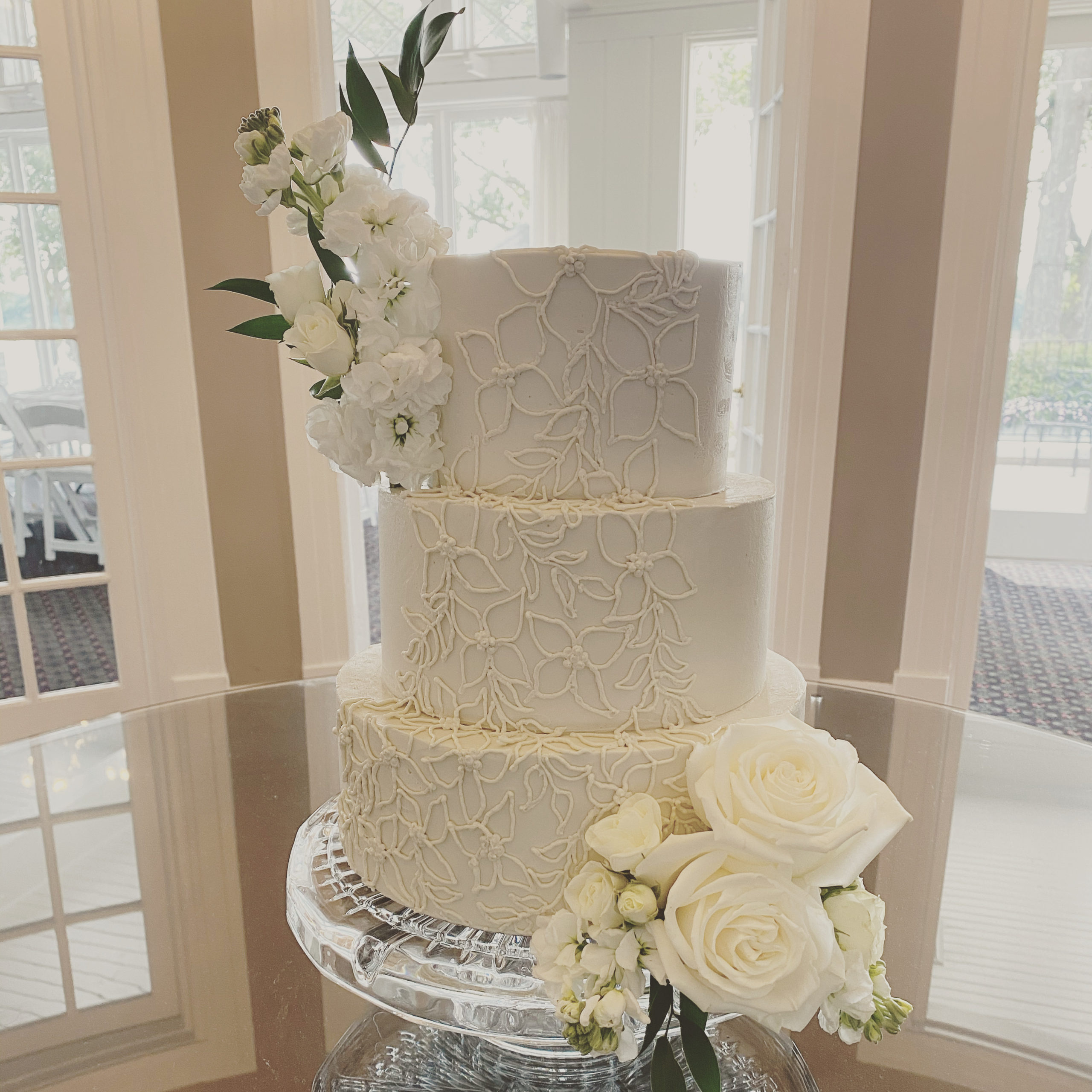 A beautiful 3-tier custom wedding cake with intricate piping and live flowers from Village Patisserie in Toledo, Ohio