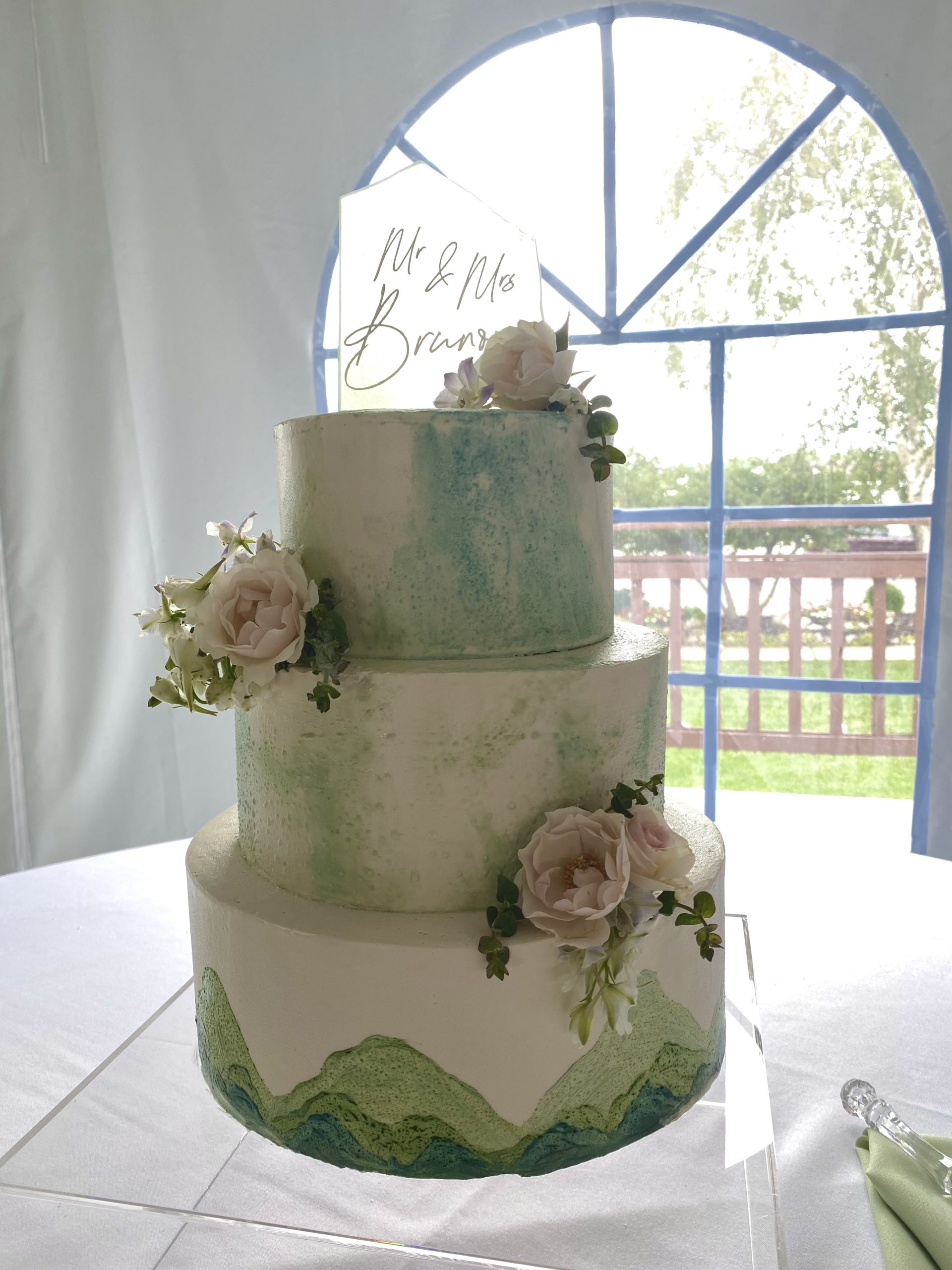 A beautiful 3-tier custom wedding cake with watercolor detail and live flowers from Village Patisserie in Toledo, Ohio