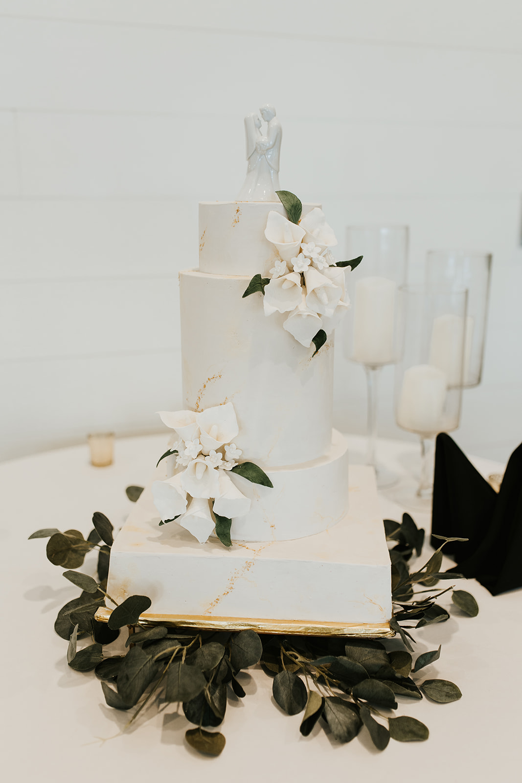 A beautiful 4-tier custom wedding cake with gold leaf and live flowers from Village Patisserie in Toledo, Ohio