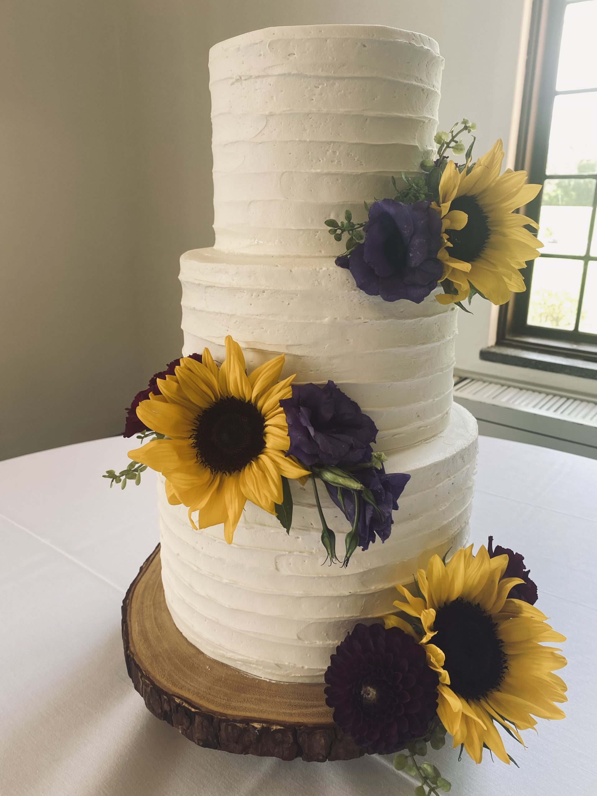 A beautiful 3-tier custom wedding cake with horizontal texture and live flowers from Village Patisserie in Toledo, Ohio
