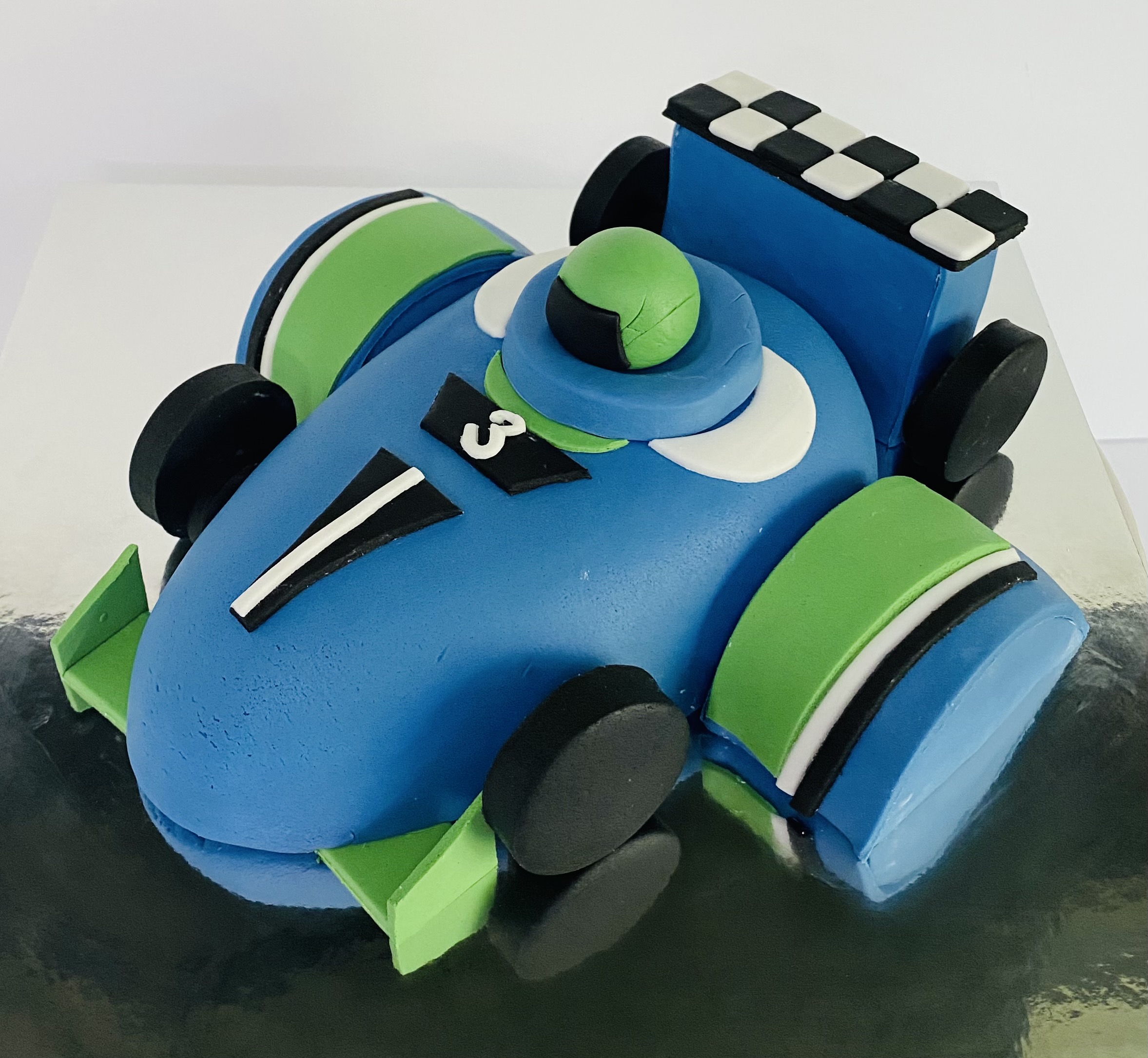 A fantastic race car themed birthday cake with hand-crafted fondant decorations from Village Patisserie in Toledo, Ohio
