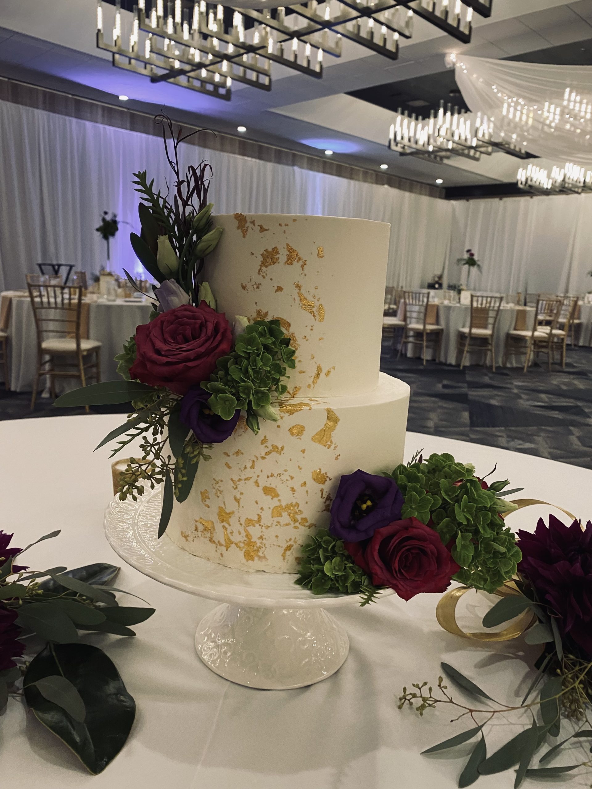 A beautiful 2-tier custom wedding cake with gold leaf and fresh flowers from Village Patisserie in Toledo, Ohio
